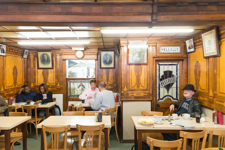 A wood-panelled interior of an east London cafe with customers.