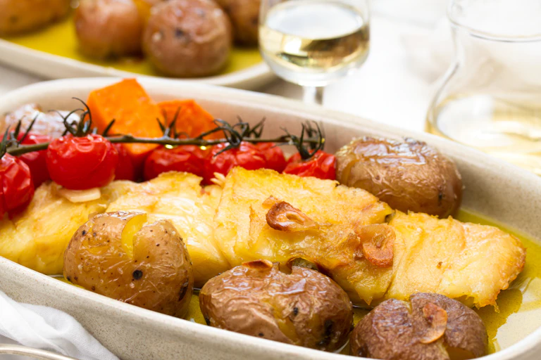 Roasted white fish with tomatoes and potatoes.