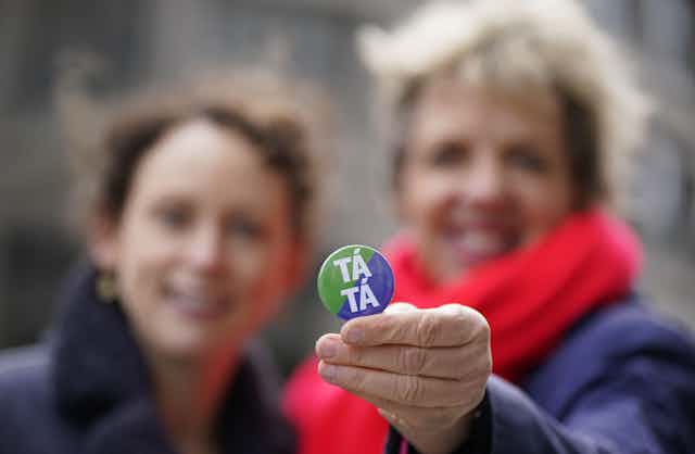 A Labout campaigner holding up a badge that says 'Tá Tá'