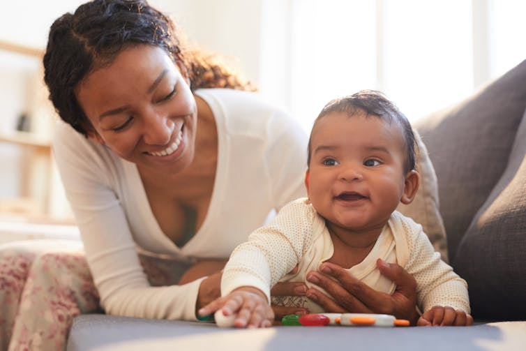Woman and baby play on a couch