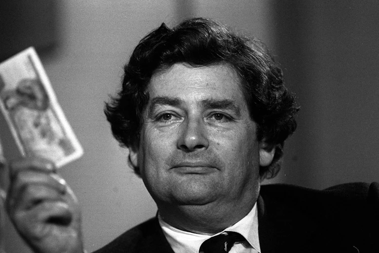 Nigel Lawson holding a £5 note.
