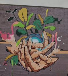 Mural of a hand holding a growing plant.