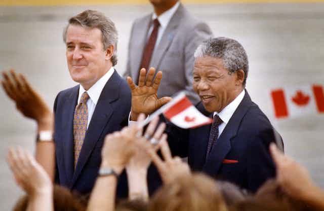 Mulroney smiling and Mandela waving