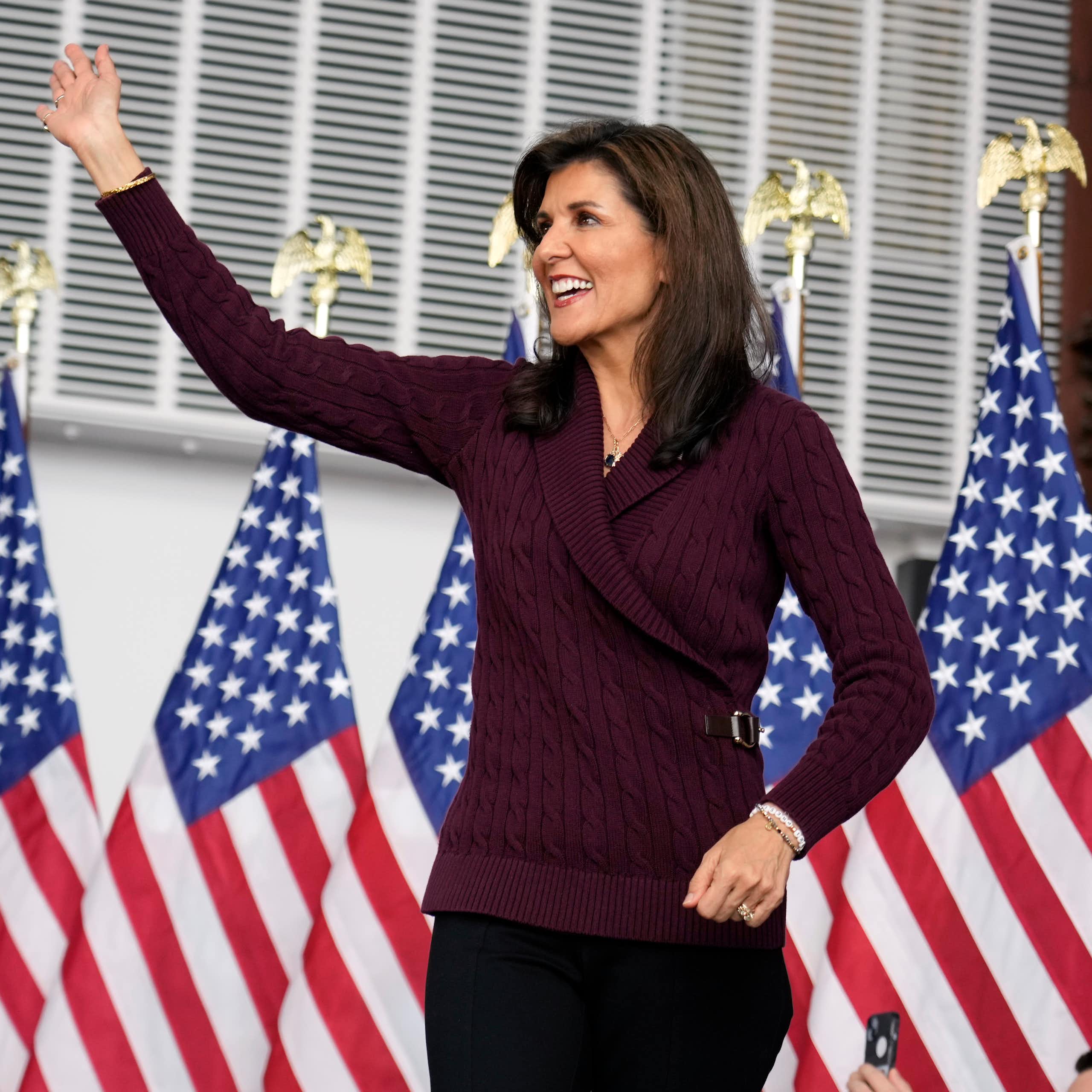 La candidate Nikki Haley se tient sur une tribune, avec des drapeaux américains en arrière-plan