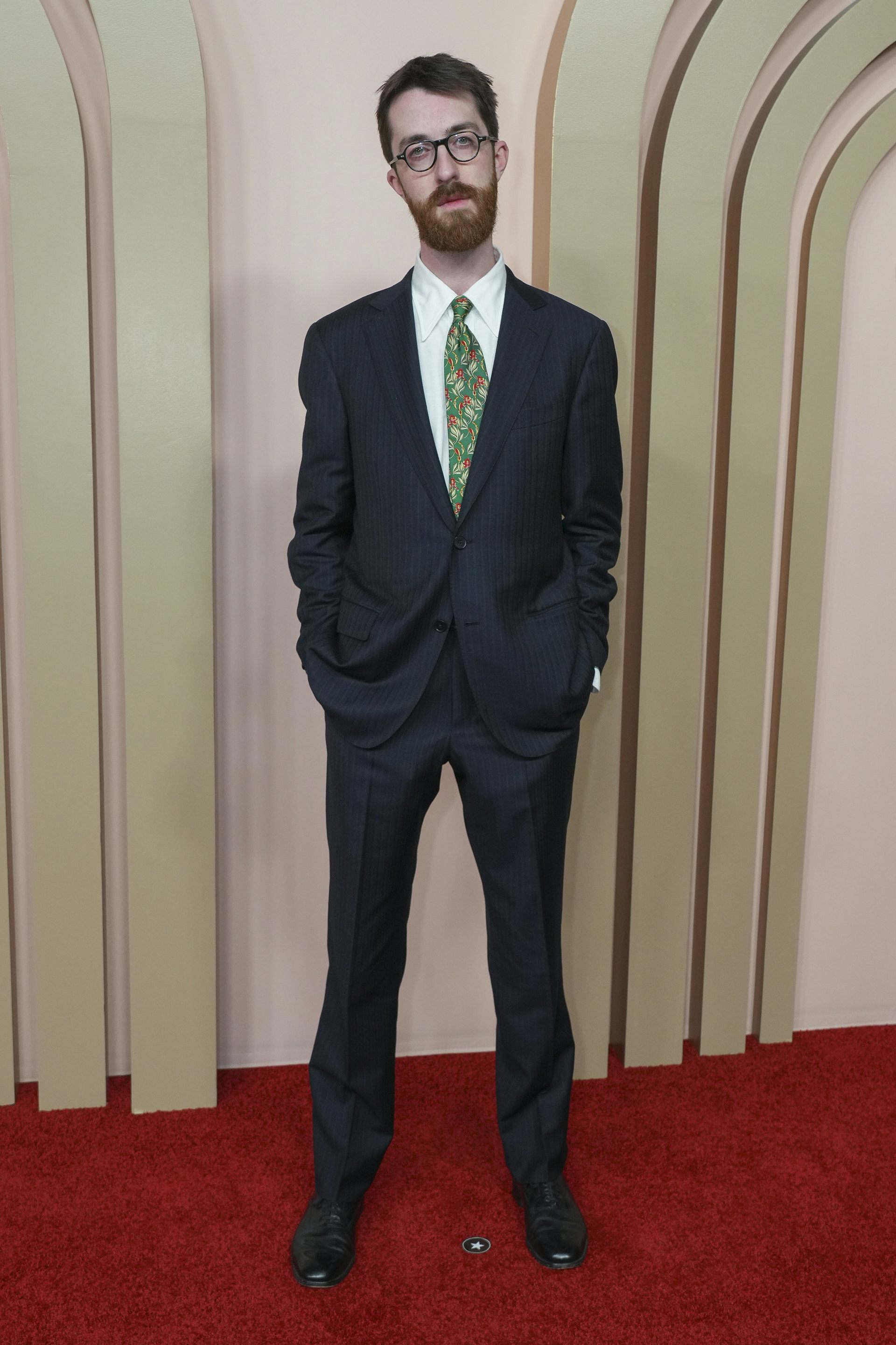 A man on a red carpet in a suit.