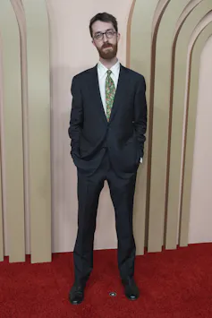 A man on a red carpet in a suit.