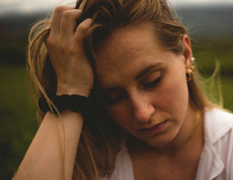 Woman holds her head, looking stressed