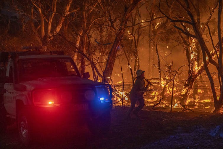 firefighter and police car near flames