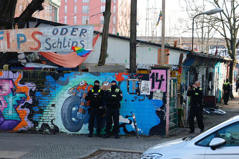 Police raiding a run down looking aras with graffiti on the walls.