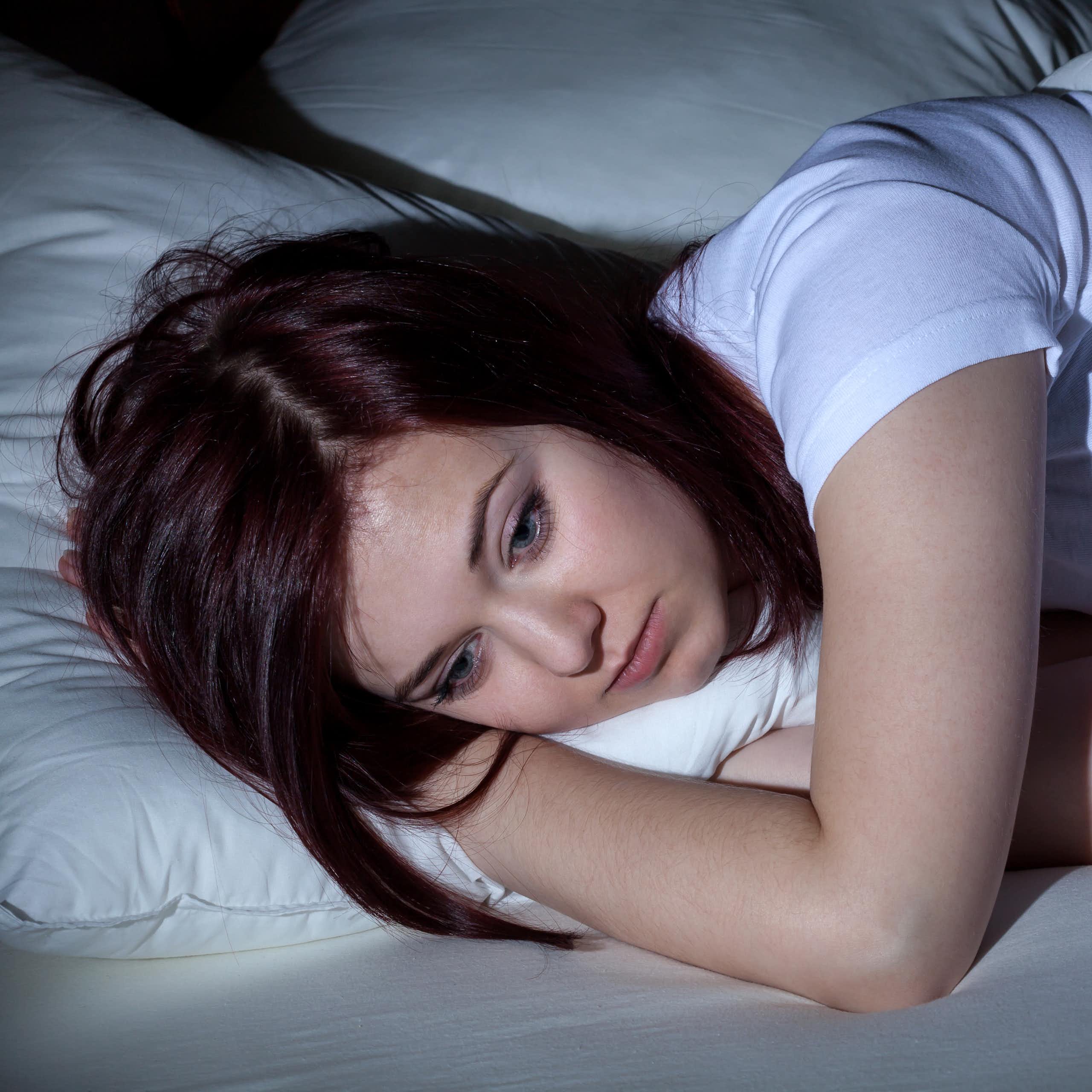 Une jeune femme est allongée dans son lit et semble peiner à trouver le sommeil.