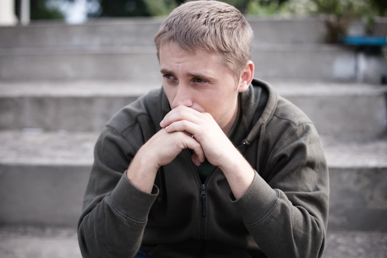 Sad young man sat on steps outside
