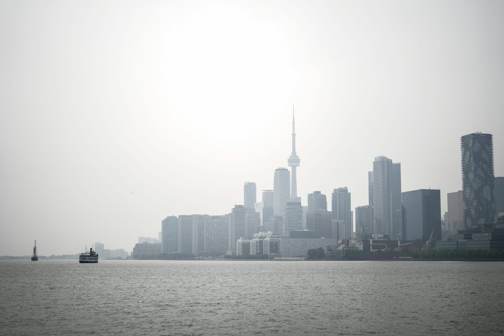 A smoky cityscape with water and boats in the foreground.