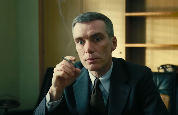 Movie still of emaciated man holding a cigarette and looking shell-shocked.