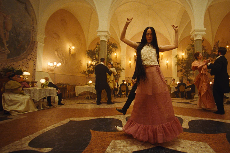 A woman seen sancing with arms raised.