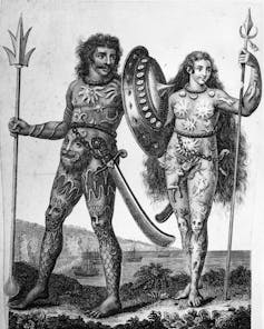 A black and white illustration showing a man and woman covered in body art, holding spears in their hands.