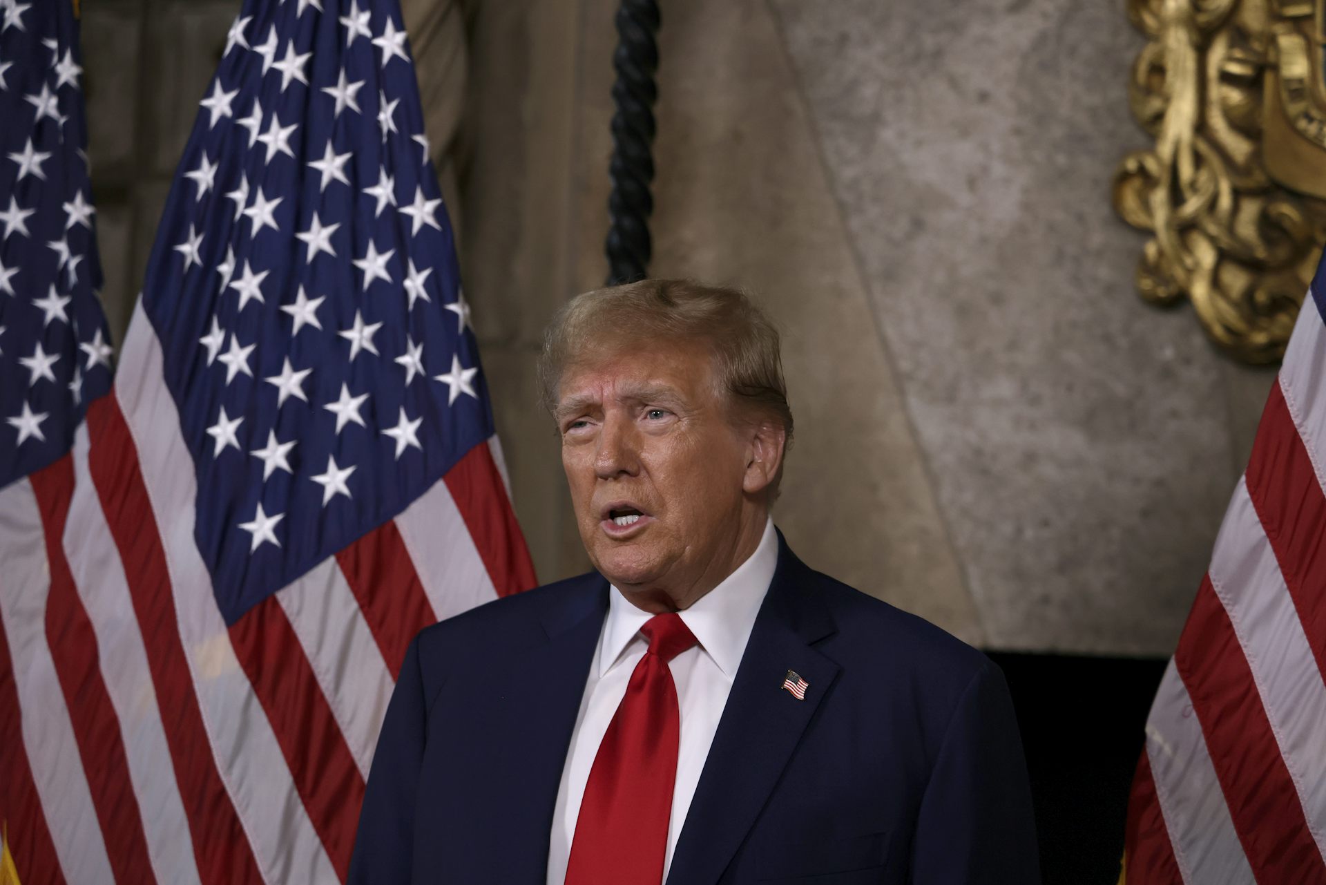Donald Trump flanked by US flags