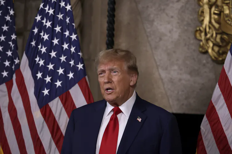 Donald Trump flanked by US flags