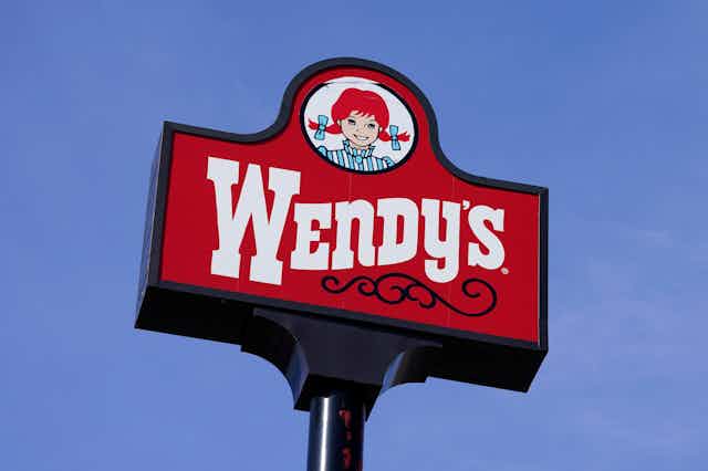 A Wendy's restaurant sign seen against a blue sky