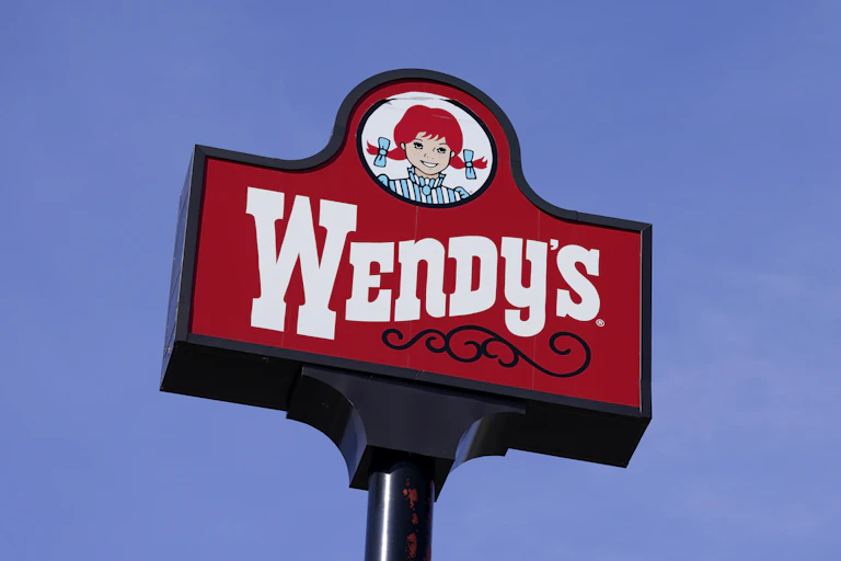 A Wendy's restaurant sign seen against a blue sky
