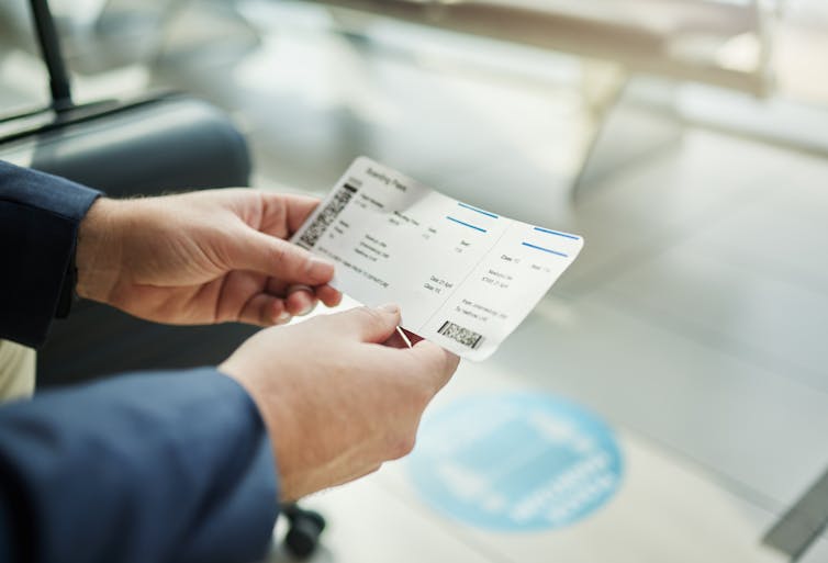 Close-up of a pair of hands holding a plane ticket