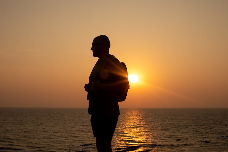 A man who is balding is admiring a sunset.
