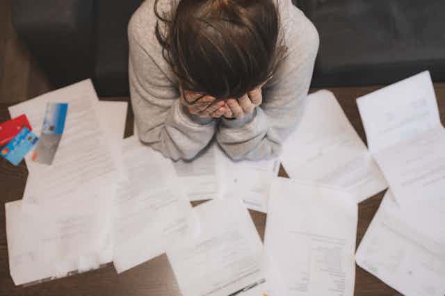 A woman holding her head in her hands while looking at paperwork