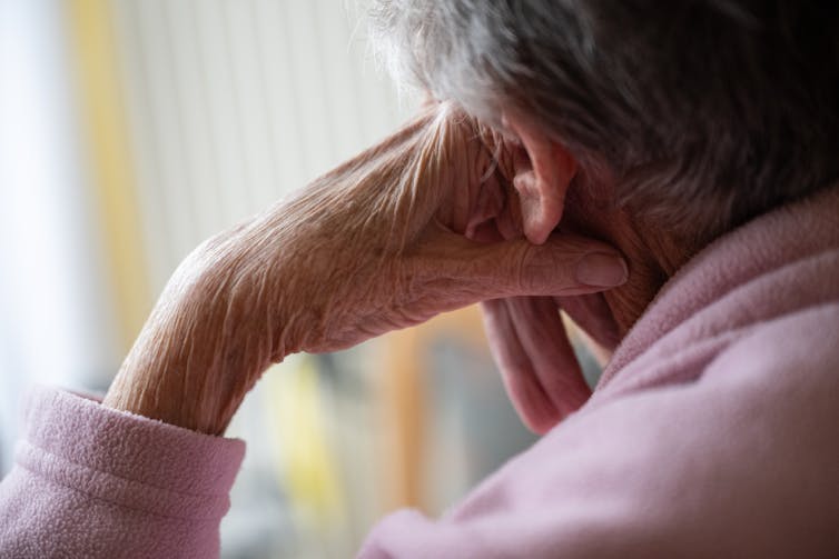 Close-up of an elderly woman's head leaning on her hand