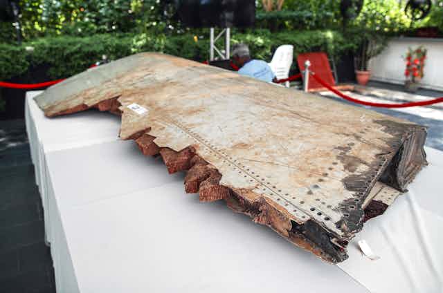 Close-up of a brown stained jagged piece of plane wing.