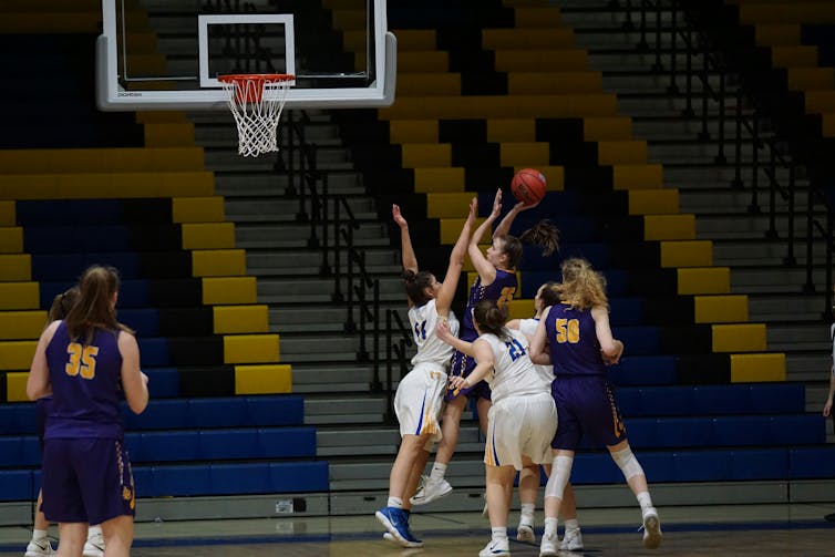 A group of young women play basketball on an indoor court.