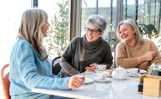 women eat and laugh together around a table