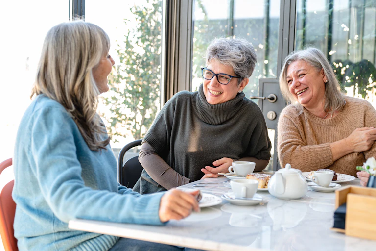 women eat and laugh together around a table