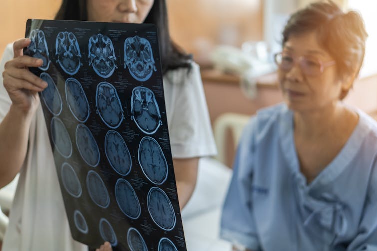 medical clinician shows woman a sheet of brain scans