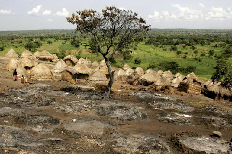 Picture of a resident of the Obim Rock Internally Displaced Persons camp surveying the damage from a fire that destroyed about 30 grass huts June 6, 2005 in Lira District, Uganda.