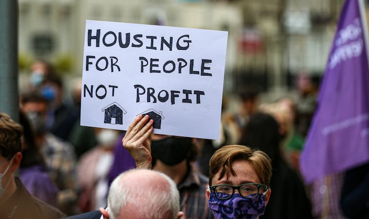 Protestors hold up a sign saying 'Housing for people not profit'