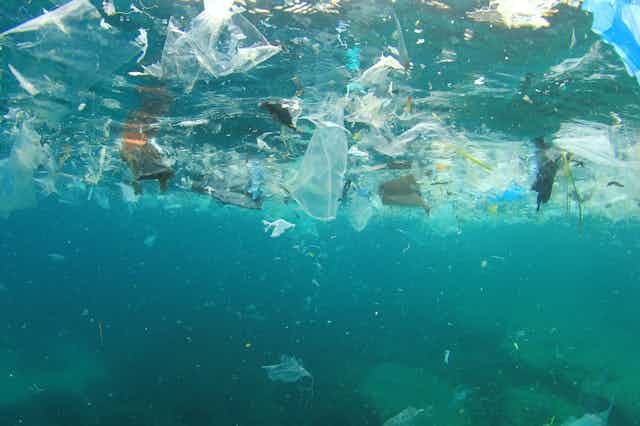 UNderwater shot of blue sea, white and coloured plastic floating litter near the surface