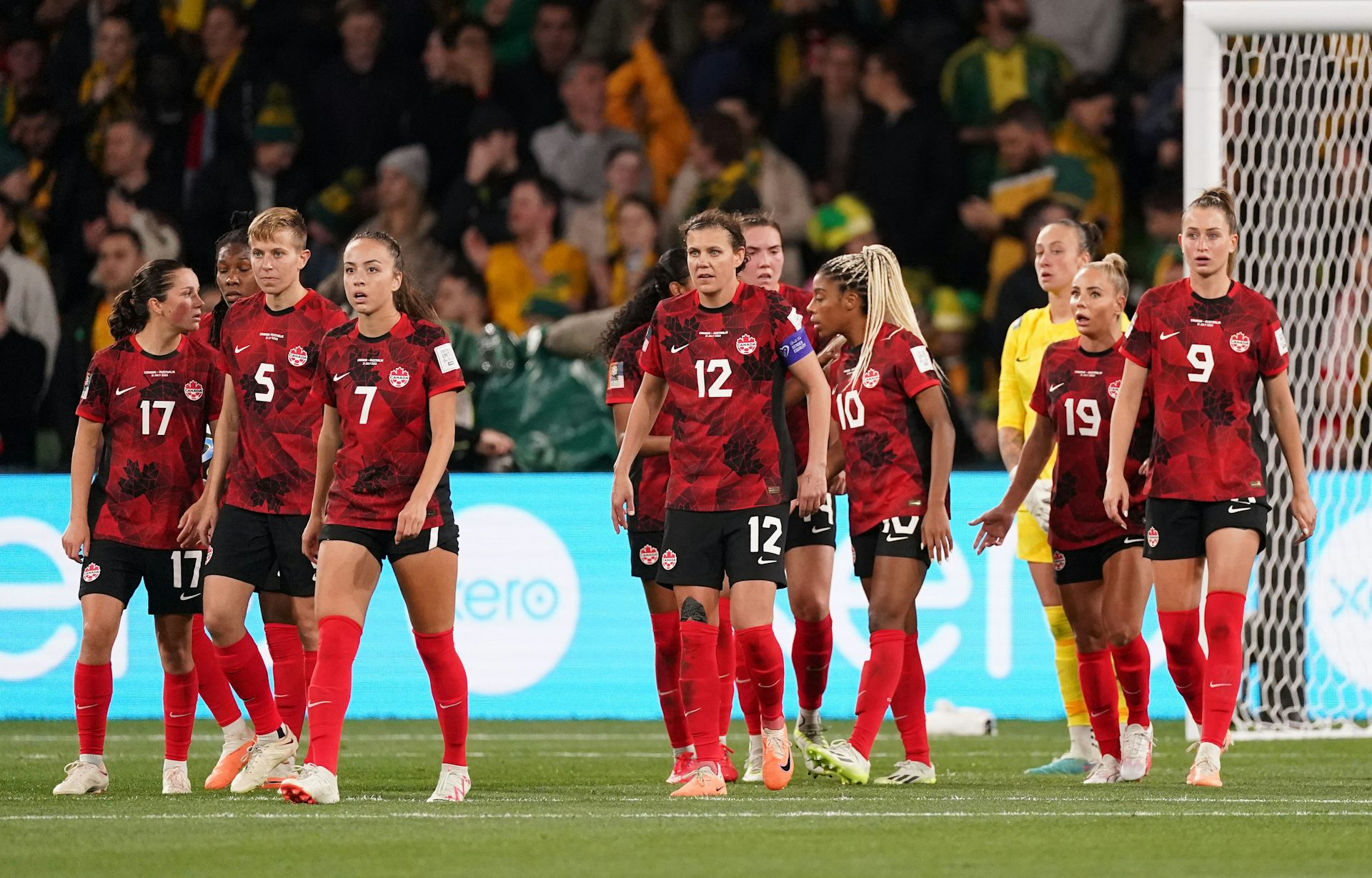 A group of women in red and black soccer uniforms standing on a field