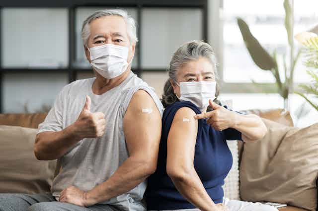 Two senior citizens -- husband and wife -- show off their arm bandages that cover their COVID-19 shots.