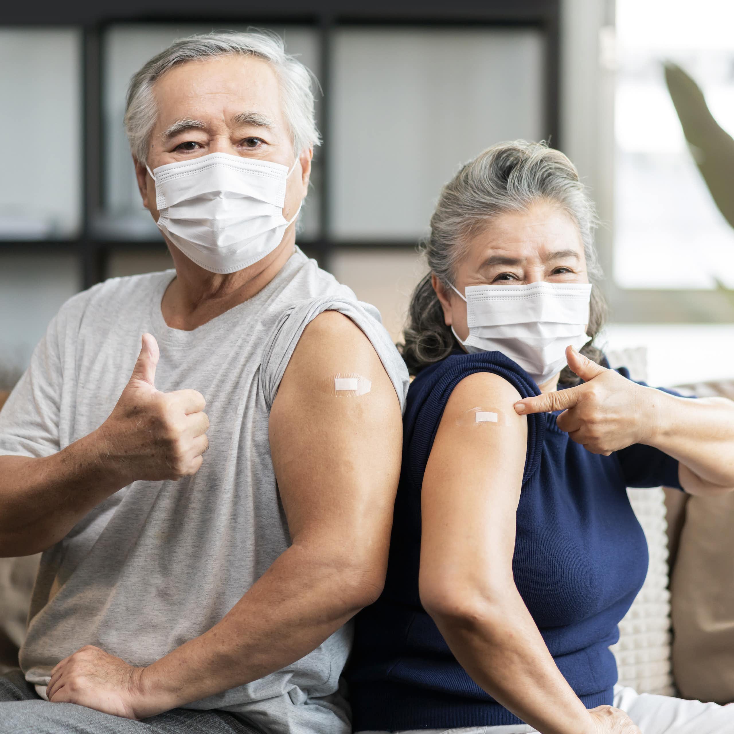 Two senior citizens -- husband and wife -- show off their arm bandages that cover their COVID-19 shots.