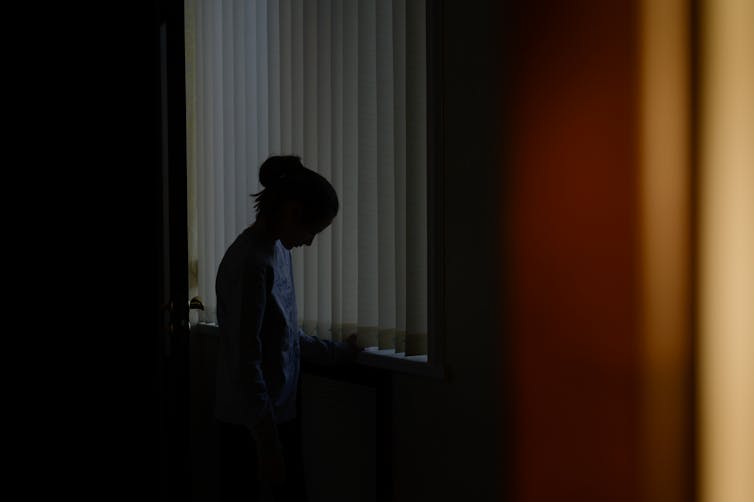The silhouette of a woman looking down in a dark room