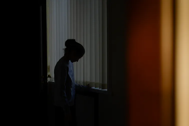 The silhouette of a woman looking down in a dark room
