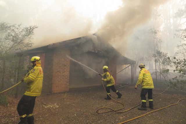 Firefighters try to protect a house in a bushfire in 2019