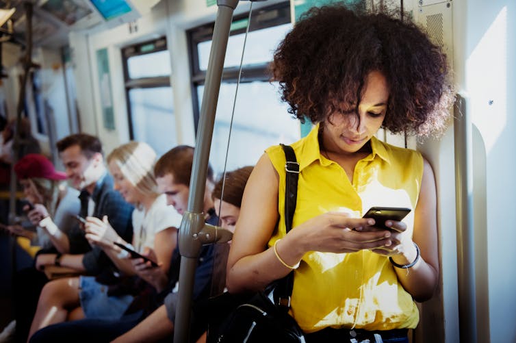 A woman uses her smartphone on public transport.