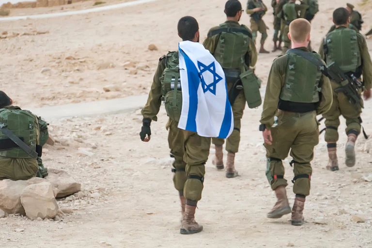 Several Israeli soldiers walking with an Israel flag.