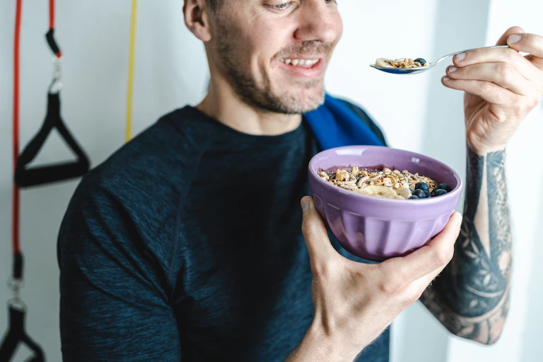 A man eats porridge in his home gym.