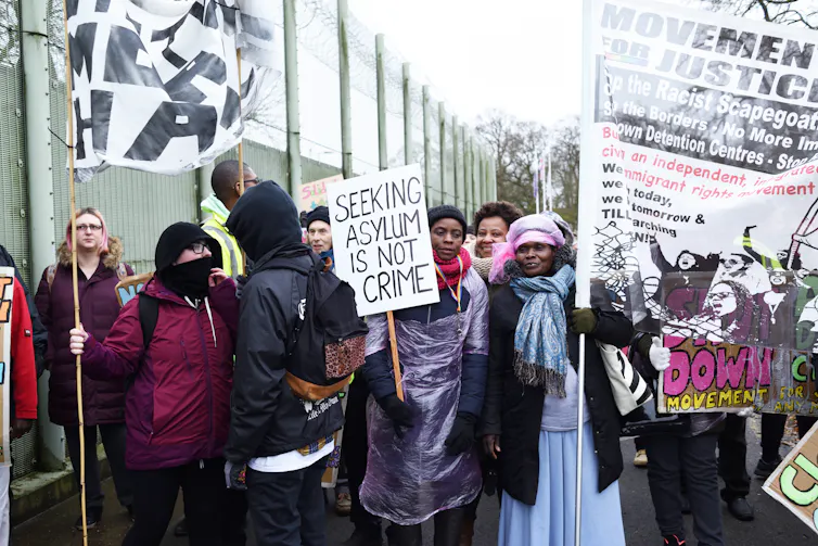 Protestors hold up posters.