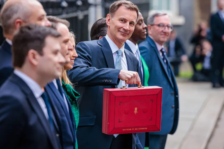 Jeremy Hunt holding up his red ministerial box during a photocall alongside other treasury ministers.