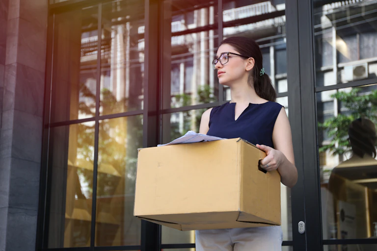 Une femme avec un carton sortant d'un bâtiment