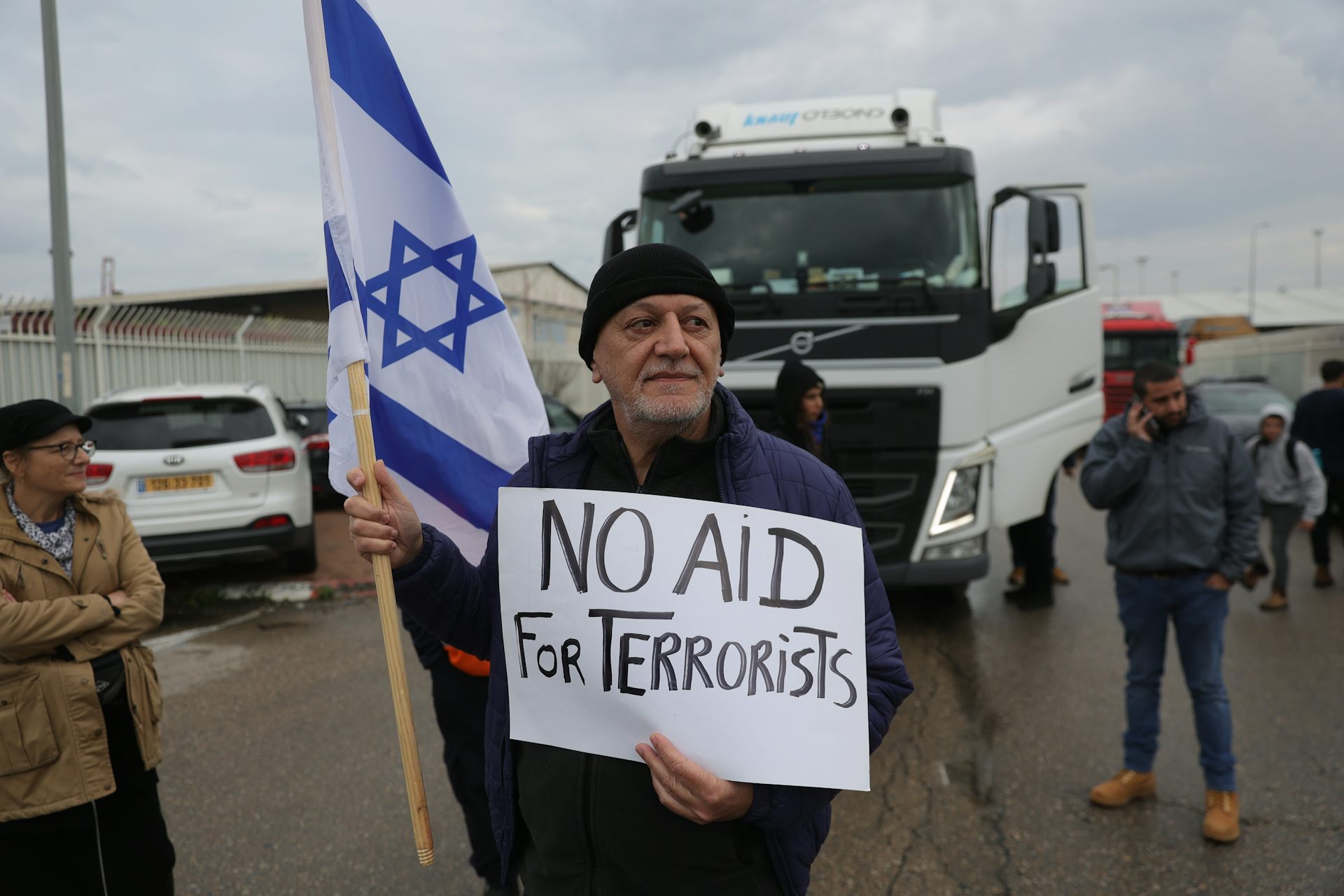 A man stands in front of an aid truck destined for Gaza carrying an Israeli flag and a sign reading: 'No aid for terrorists'.