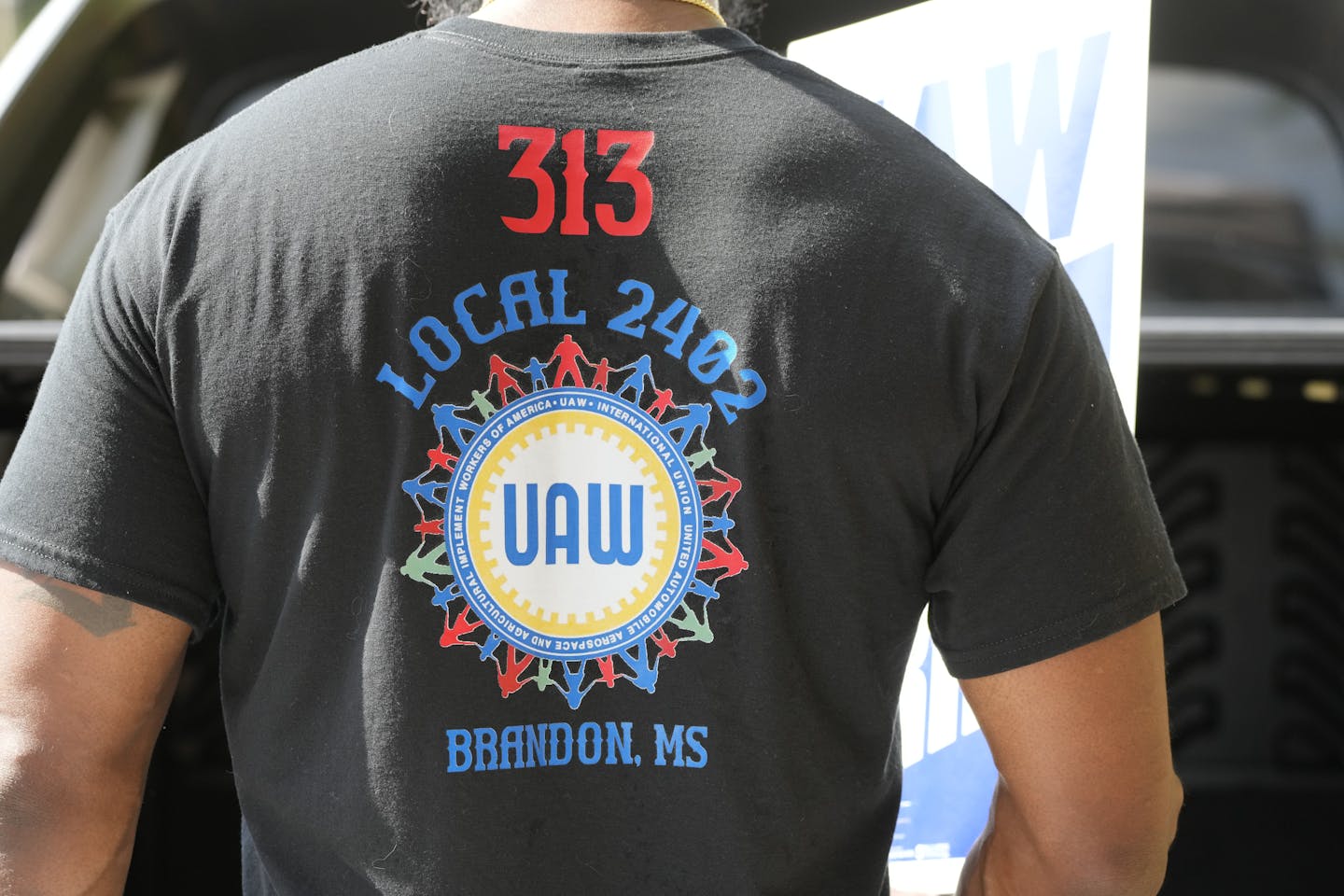 The back of a worker wearing a UAW t-shirt indicating employment in Brandon, Miss.