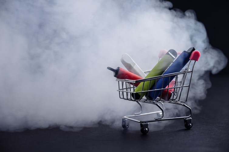 Vapes in a shopping trolley surrounded by smoke.